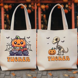 May include: Off-white canvas tote bags with Halloween-themed designs. One features a cartoon pumpkin driving a monster truck, the other a dinosaur skeleton with a pumpkin. Both bags have the name "Tucker" in orange.