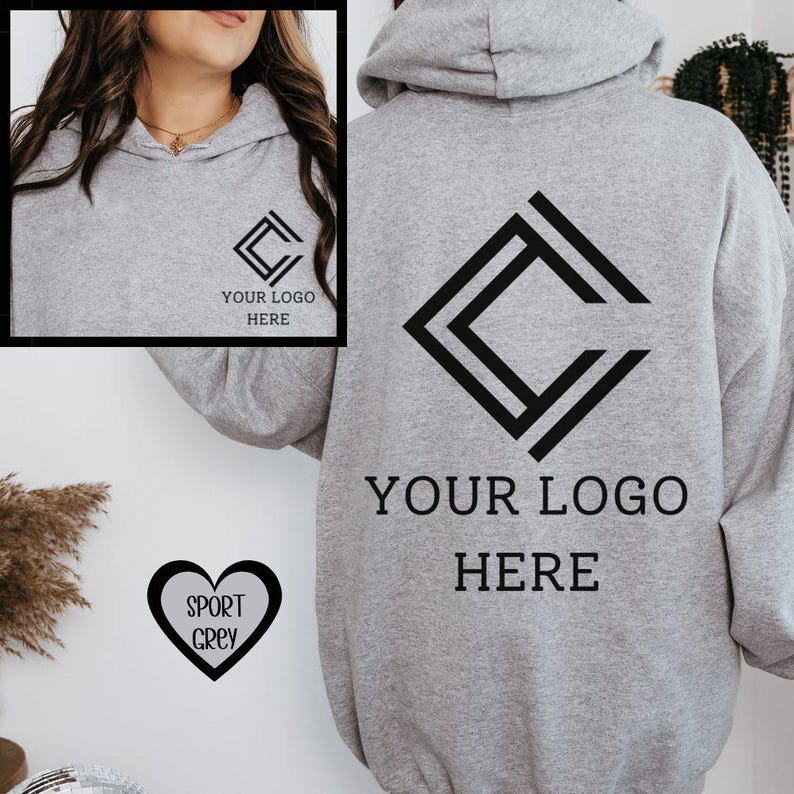 K&ouml;nnte beinhalten: Ein hellgrauer Kapuzenpullover mit einem schwarzen geometrischen Logo und dem Text "YOUR LOGO HERE". Das Design wiederholt sich auf der Vorderseite. Eine herzf&ouml;rmige Grafik mit dem Text "SPORT GREY" ist ebenfalls sichtbar. Der Hoodie hat eine Kapuze.