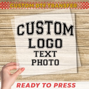 May include: A clear transfer sheet with the words "CUSTOM LOGO TEXT PHOTO" in a bold, black, collegiate-style font. The words "CUSTOM DTF TRANSFER" and "READY TO PRESS" are also visible in the image.
