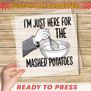May include: DTF transfer with the text "I'M JUST HERE FOR THE MASHED POTATOES." The image shows a cartoon hand holding a whisk over a bowl of mashed potatoes. The words "READY TO PRESS" are at the bottom.