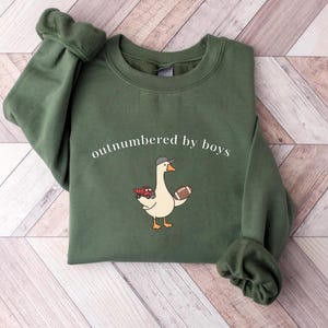 "Outnumbered by Boys Duck Sweatshirt, Funny Mom Shirt with Football and Truck Design, Personalized Family Apparel, Casual Gift for Mom" Outnumbered by boys, Funny mom sweatshirt, Personalized family tee, Duck graphic shirt, Football mom shirt, Truck design sweatshirt, Family gift idea, Mom shirt with kids, Cute mom sweater, Family matching shir, Casual mom outfit, Custom mom apparel, Funny family sweatshirt,