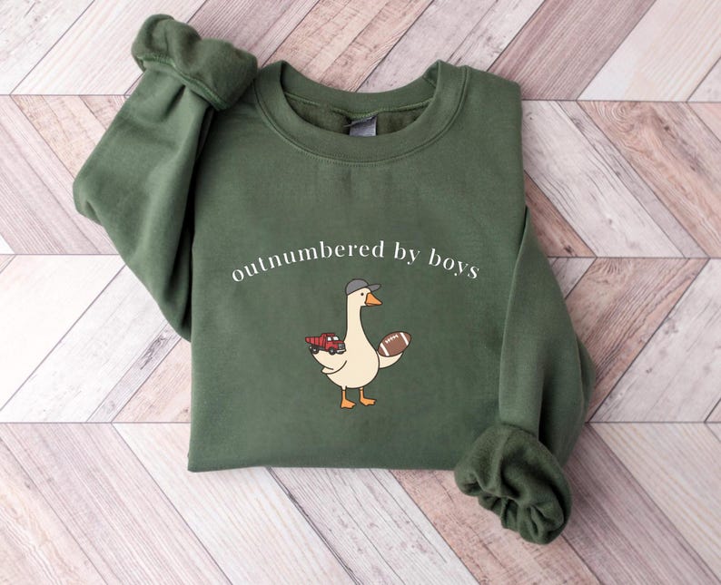 "Outnumbered by Boys Duck Sweatshirt, Funny Mom Shirt with Football and Truck Design, Personalized Family Apparel, Casual Gift for Mom" Outnumbered by boys, Funny mom sweatshirt, Personalized family tee, Duck graphic shirt, Football mom shirt, Truck design sweatshirt, Family gift idea, Mom shirt with kids, Cute mom sweater, Family matching shir, Casual mom outfit, Custom mom apparel, Funny family sweatshirt,