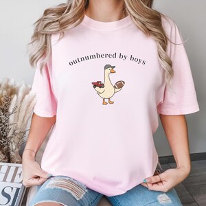 "Outnumbered by Boys Duck Sweatshirt, Funny Mom Shirt with Football and Truck Design, Personalized Family Apparel, Casual Gift for Mom" Outnumbered by boys, Funny mom sweatshirt, Personalized family tee, Duck graphic shirt, Football mom shirt, Truck design sweatshirt, Family gift idea, Mom shirt with kids, Cute mom sweater, Family matching shir, Casual mom outfit, Custom mom apparel, Funny family sweatshirt,