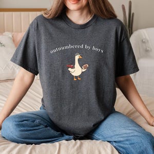"Outnumbered by Boys Duck Sweatshirt, Funny Mom Shirt with Football and Truck Design, Personalized Family Apparel, Casual Gift for Mom" Outnumbered by boys, Funny mom sweatshirt, Personalized family tee, Duck graphic shirt, Football mom shirt, Truck design sweatshirt, Family gift idea, Mom shirt with kids, Cute mom sweater, Family matching shir, Casual mom outfit, Custom mom apparel, Funny family sweatshirt,