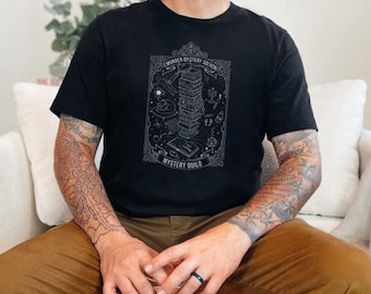 May include: A black short-sleeve t-shirt featuring a white line-art graphic of a stack of books, a magnifying glass, and a skull. The text reads Murder Mystery Solver and Mystery Guild, enclosed within an ornate rectangular frame on the chest.