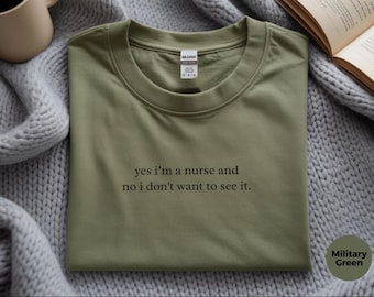 May include: A military green short-sleeved t-shirt with a crew neckline. The shirt features black embroidered text centered on the chest that reads, yes i'm a nurse and no i don't want to see it. A white brand label is visible at the inner neck.