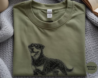 May include: A military green crew neck t-shirt featuring a black line art illustration of a Rottweiler dog with its tongue out. The shirt has a Gildan brand label at the inner neckline and is made of cotton. The graphic is centered on the chest.