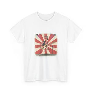 May include: Military green t-shirt featuring a cartoon flamingo playing a bass guitar on a stage with a red and white sunburst background. The flamingo wears sunglasses and a black vest. A microphone stands nearby.