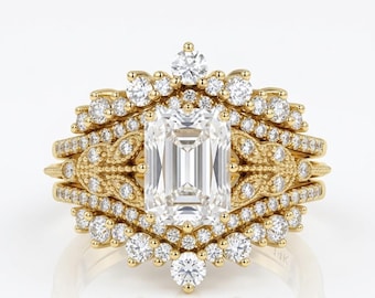 May include: A gold engagement ring set featuring an emerald-cut center stone surrounded by smaller diamonds. The ring has a detailed, ornate design with multiple bands and a halo of accent stones, creating a luxurious and elegant look.
