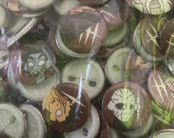 May include: A close-up of a bag filled with various round buttons. The buttons are mostly brown with white accents and feature different graphic designs. Some buttons have a white background with a black pin.