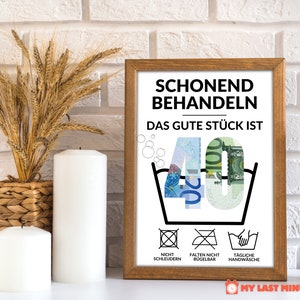 May include: A framed print with a humorous message about turning 40. The print features a washing instruction symbol with the number 40 inside, made of euro bills. The text reads "Schonend Behandeln Das Gute St&uuml;ck Ist 40" and includes additional washing instructions: "Nicht Schleudern", "Falten Nicht B&uuml;gelbar", and "T&auml;gliche Handw&auml;sche".