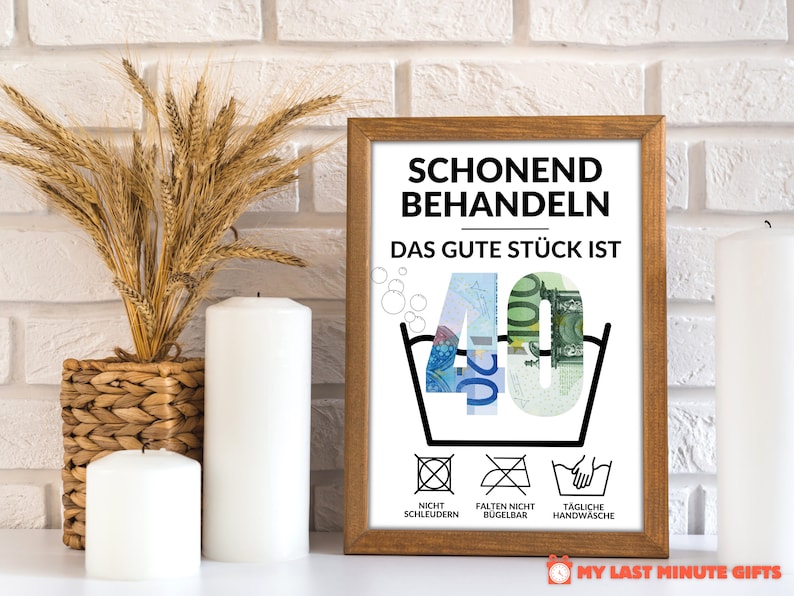 May include: A framed print with a humorous message about turning 40. The print features a washing instruction symbol with the number 40 inside, made of euro bills. The text reads "Schonend Behandeln Das Gute St&uuml;ck Ist 40" and includes additional washing instructions: "Nicht Schleudern", "Falten Nicht B&uuml;gelbar", and "T&auml;gliche Handw&auml;sche".