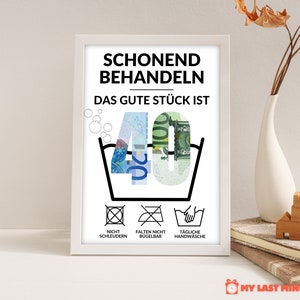May include: A white framed print with black text that reads "Schonend Behandeln Das Gute St&uuml;ck Ist 40". The number 40 is made of euro bills. Below the text are three symbols: a circle with an X through it, a circle with an X through it and a diagonal line, and a hand washing symbol. The text below the symbols reads "Nicht Schleudern Falten Nicht B&uuml;gelbar T&auml;gliche Handw&auml;sche".