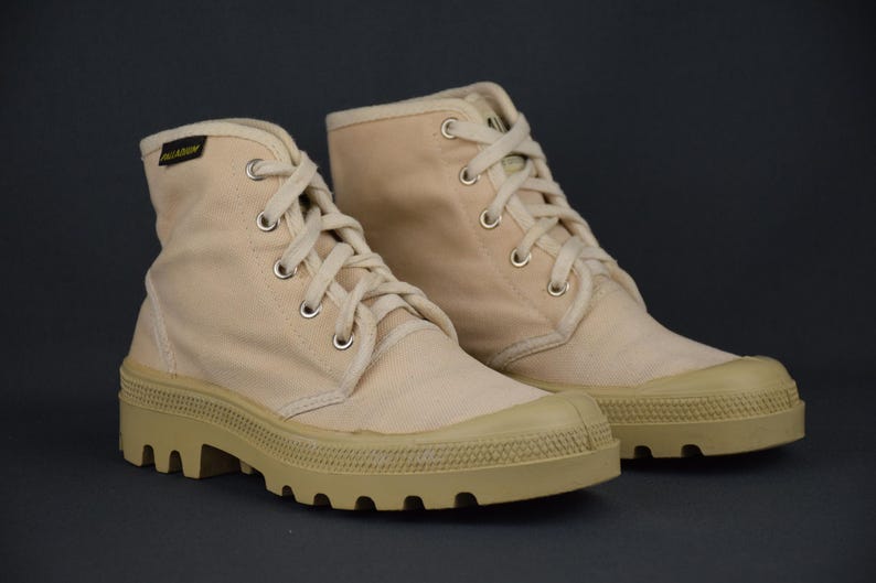 Puede incluir: Un par de botas altas de lona beige con suelas gruesas y robustas. Las botas tienen cordones blancos y est&aacute;n hechas de una tela suave y transpirable.