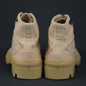 Puede incluir: Un par de botas altas de lona de color rosa claro con una suela de goma beige gruesa.