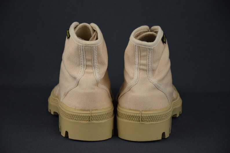 Puede incluir: Un par de botas altas de lona de color rosa claro con una suela de goma beige gruesa.