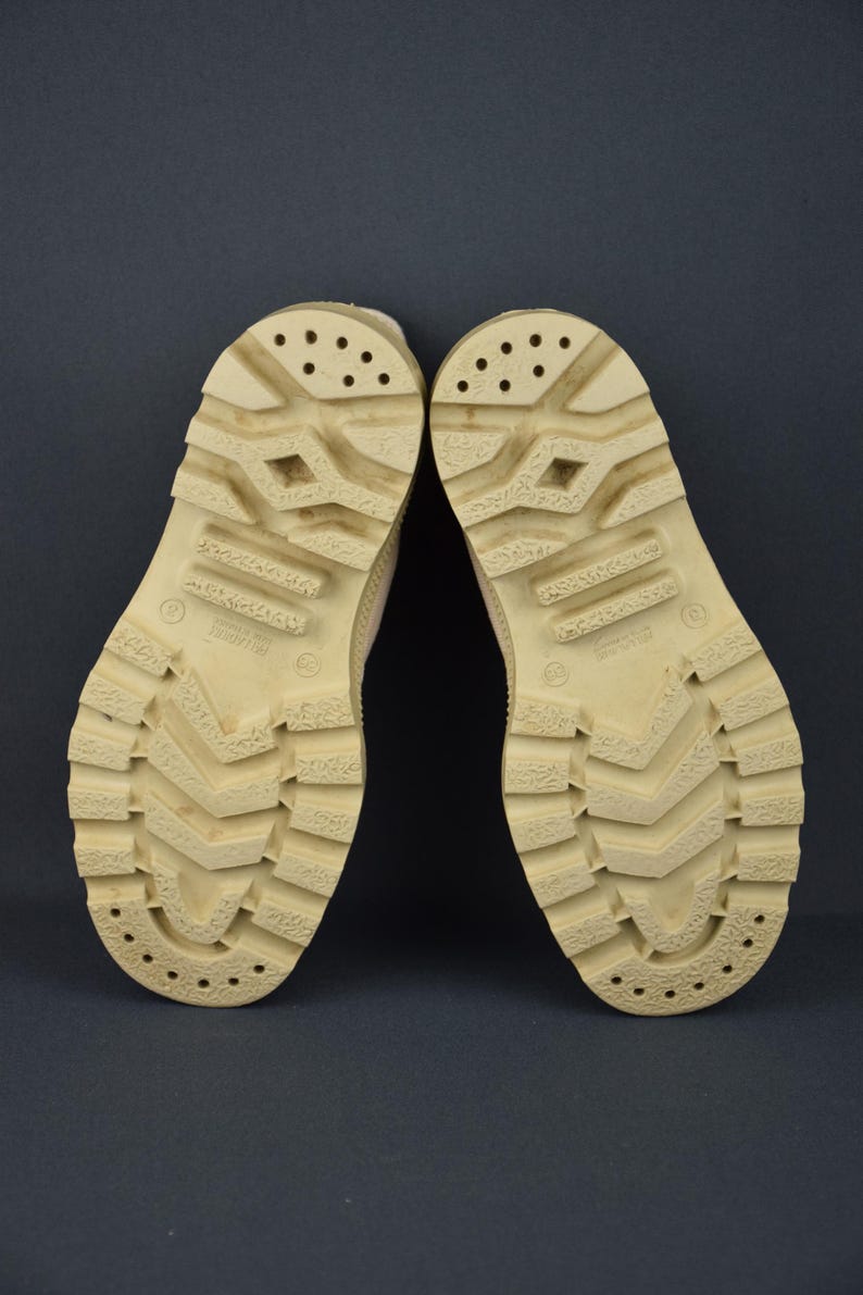 Puede incluir: Un par de botas de cuero color beige con una suela gruesa de goma. Las suelas tienen un patr&oacute;n de banda de rodadura y est&aacute;n marcadas con la palabra "Imitation".