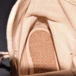 Puede incluir: El interior de una zapatilla de lona blanca con una plantilla tejida marr&oacute;n.