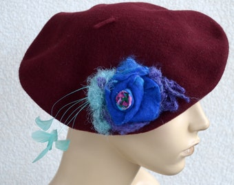 Burgundy beret with felted and feathered embellishment.