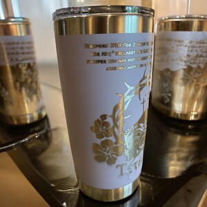 May include: A white stainless steel tumbler with a gold lid and gold lettering. The tumbler has a gold design of a crown of thorns, flowers, and a cross. The text on the tumbler reads "Jeremiah 29:11 For I know the plans I have for you" declares the Lord, "plans to prosper you and not to harm you, plans to give you hope and a future."
