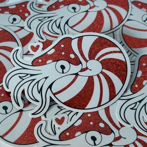 May include: A set of stickers featuring a cartoon nautilus with a red and white striped shell. The nautilus is depicted with a large eye and tentacles. The stickers are printed on white paper with a glossy finish.