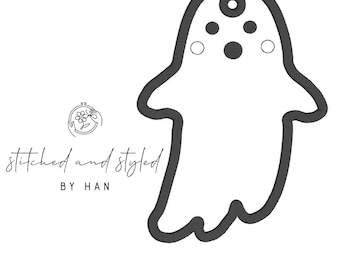 May include: A black and white graphic of a ghost with a rounded body, arms, and a head with three small circles and two small white circles. The text "stitched and styled BY HAN" is below a floral logo.