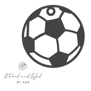 May include: A black and white soccer ball design with a small hole at the top for hanging. The text "stitched and styled BY HAN" is at the bottom. The design is a simple, clean graphic.