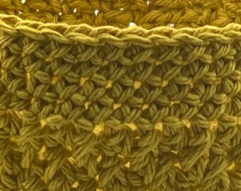 May include: A close-up of a yellow crocheted basket with a woven pattern.