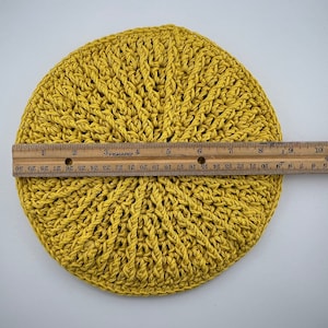Puede incluir: Un posavasos redondo de crochet amarillo que mide aproximadamente 15 cm de diámetro.