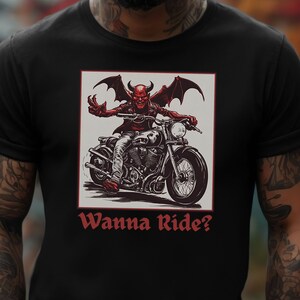 May include: A black t-shirt with a graphic of a red devil riding a motorcycle. The text "Wanna Ride?" is printed below the graphic.