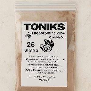 May include: A transparent bag containing brown powder, with a white label. The label says "TONIKS - Theobromine 20%" and the chemical formula C7H8N4O2. It also states "25 GRAMS" and lists benefits. Suitable for vegans.