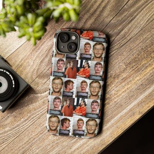 May include: A phone case with a repeating pattern of mugshot images of a man in an orange jumpsuit and glasses. The case has a black camera lens cutout and a black border. The background is a wooden surface.