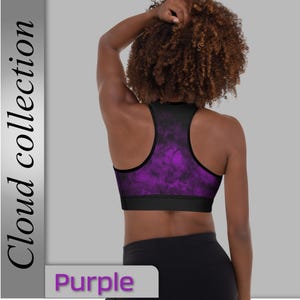 Puede incluir: Sujetador deportivo morado con ribete negro y un vibrante patrón de nubes moradas. El sujetador tiene un diseño de espalda nadadora y una banda negra ancha en la parte inferior. La palabra "Purple" se muestra en un cuadro blanco en la parte inferior de la imagen.