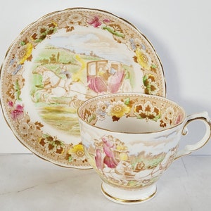 May include: A vintage teacup and saucer set. The cup and saucer feature a pastoral scene with a horse-drawn carriage and floral accents. The set has a gold trim and a cream-colored background.
