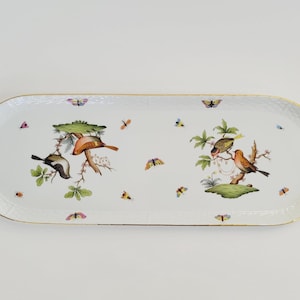 Peut inclure: Plateau de service en porcelaine blanche avec bordure et poignées dorées. Le plateau présente des oiseaux, des papillons et du feuillage peints à la main dans des tons de marron, vert et orange. Le plateau mesure environ 46 cm de long.