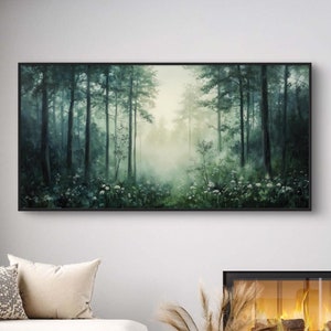 May include: A white sectional sofa with cushions sits in front of a fireplace with a black frame and a glass front. A black coffee table sits in front of the sofa. A framed painting of a misty forest hangs on the wall above the fireplace.