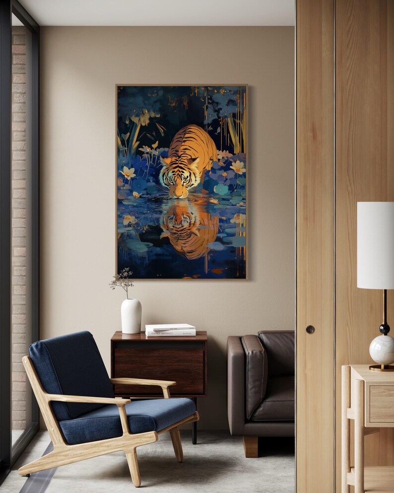 A majestic tiger drinks from a calm lake, its reflection glowing in golden hues. Surrounded by blue flowers and soft light, this art print blends nature with elegance, perfect for boho, nature, or wildlife-themed home decor.