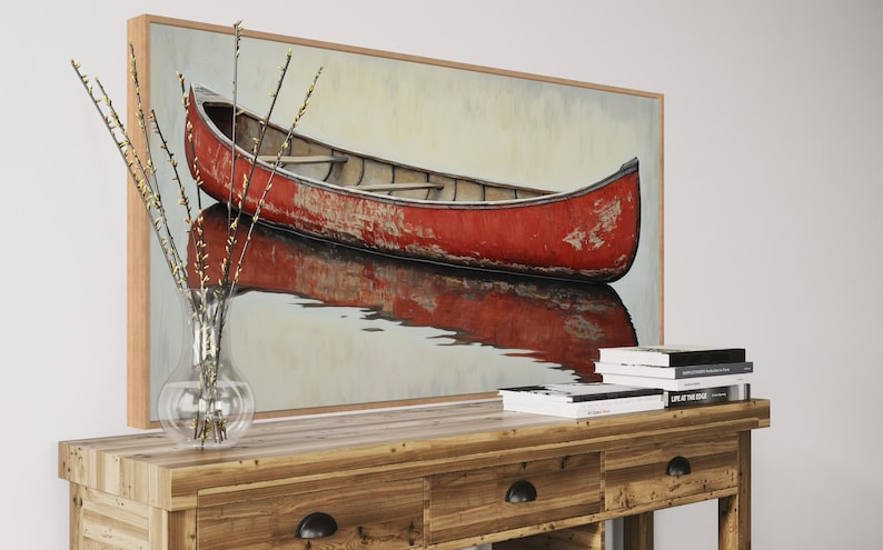 This artwork features a rustic red canoe resting serenely on calm waters. The canoe, with its weathered surface, reflects beautifully in the water, showcasing its rich color. The soft background adds a tranquil atmosphere, perfect for nature lovers.