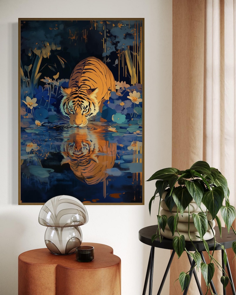 A majestic tiger drinks from a calm lake, its reflection glowing in golden hues. Surrounded by blue flowers and soft light, this art print blends nature with elegance, perfect for boho, nature, or wildlife-themed home decor.