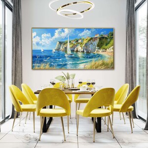 Sailboats glide on azure waters near chalky cliffs with green tops under a vast, cloud-dappled sky, portraying a serene, sunlit seascape.