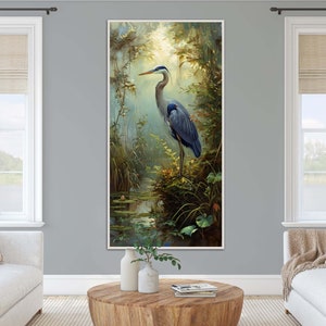 A serene Blue Heron stands amidst a lush wetland oasis, its graceful form bathed in dappled sunlight filtering through a verdant canopy. Perfect for a tranquil decor piece.