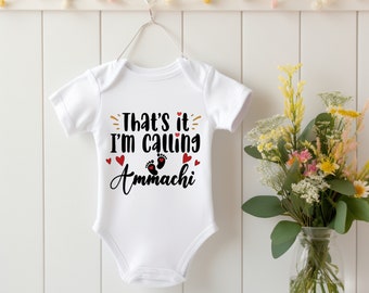 May include: White baby onesie with black text that reads "That's it I'm calling Ammachi" with red hearts and footprints.