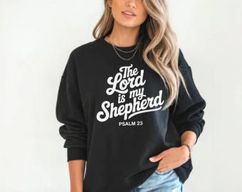 May include: Black sweatshirt with the text "The Lord is my Shepherd" in white script. The text "Psalm 23" is printed below the script. The sweatshirt is a crew neck style.