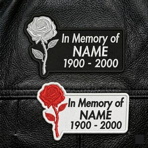 May include: Two embroidered patches with a rose design and the text "In Memory of NAME 1900 - 2000". One patch features a white rose on a black background, the other a red rose on a white background. The patches are likely for a jacket or vest.