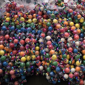 May include: A large collection of colorful wrapped candies, tied together with ribbons, creating a festive and decorative display.