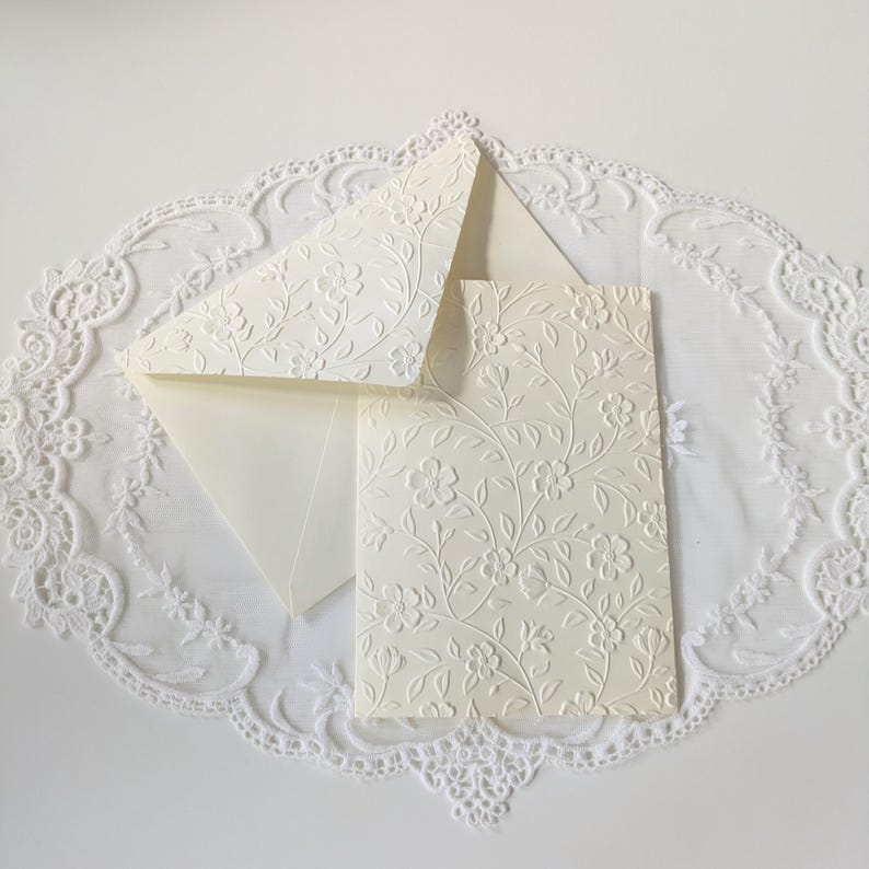 Ivory-colored stationery set featuring a floral embossed design. The set includes cards and envelopes that are embossed with a floral pattern.