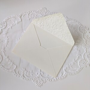 Shows the inside of the embossed ivory envelope to pair with the ivory card. Envelope flap is embossed with a floral vine design.