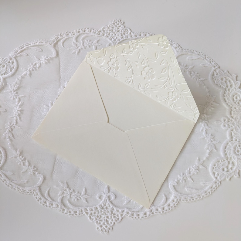 Shows the inside of the embossed ivory envelope to pair with the ivory card. Envelope flap is embossed with a floral vine design.