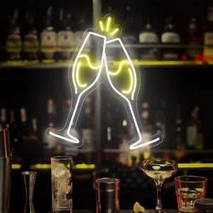 May include: Neon sign of two champagne glasses clinking together in a bar setting. The sign is yellow and white and is hanging above a bar counter with various glasses and bar tools.