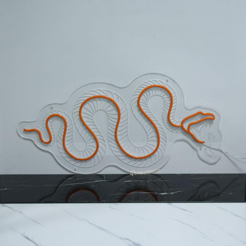May include: Orange neon snake design on a white wall. The snake is outlined in white and has a textured pattern.